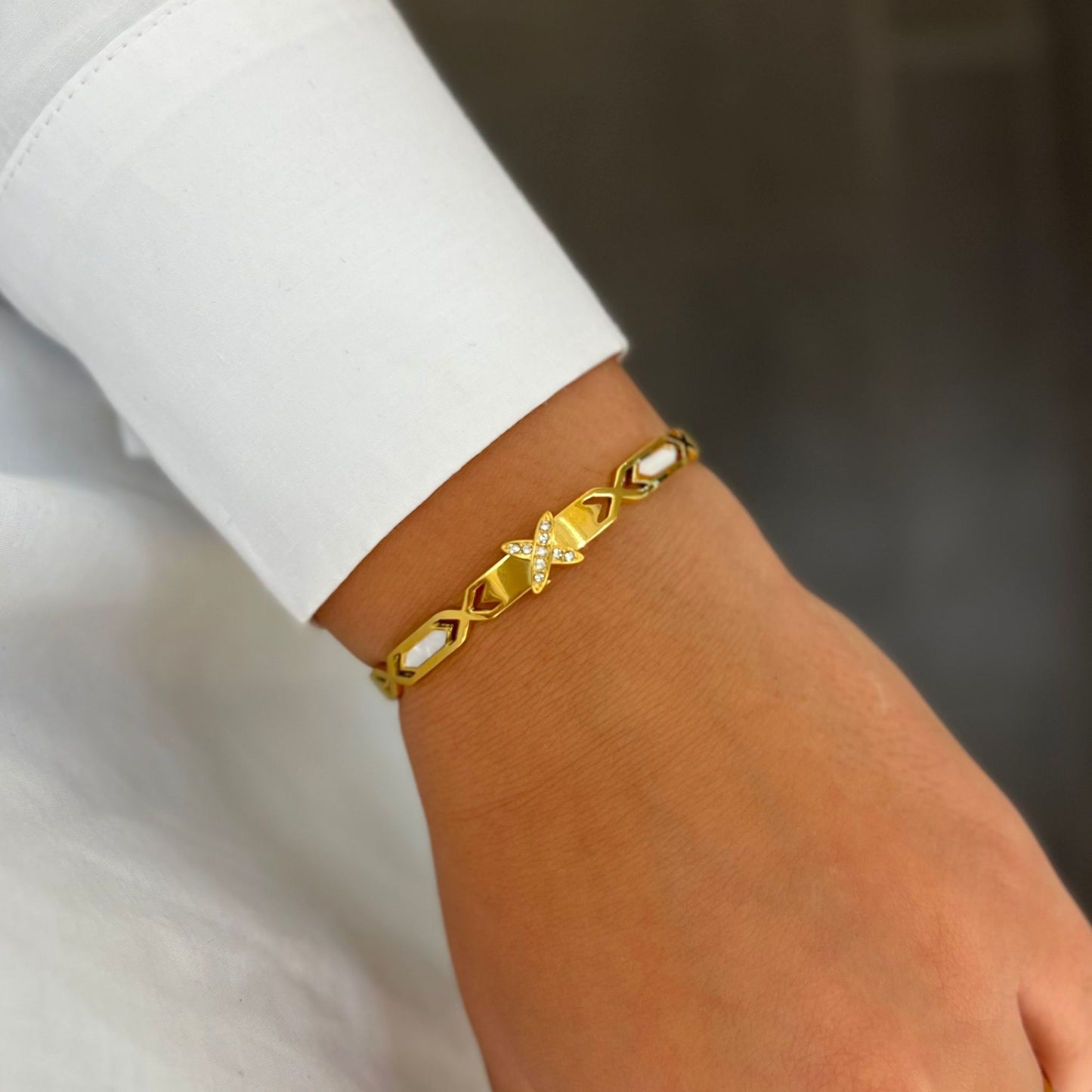 Armreif mit stilisiertem Kreuz und funkelnden Akzenten